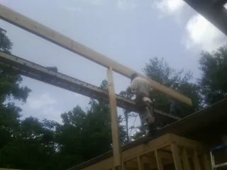 Carpenter setting a ridge beam over a new addition frame — Ice Dam Removal by Roofing Brothers in Waveland