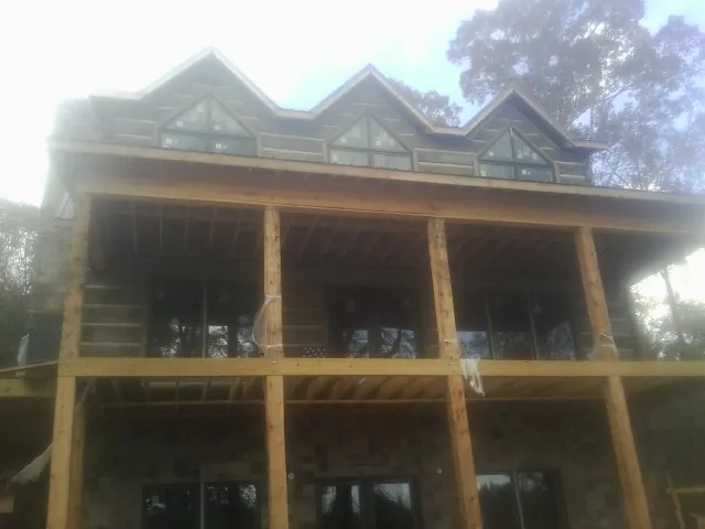 Dormers and porch framing on a large log home under construction — Roof Coating work by our crew in Waveland