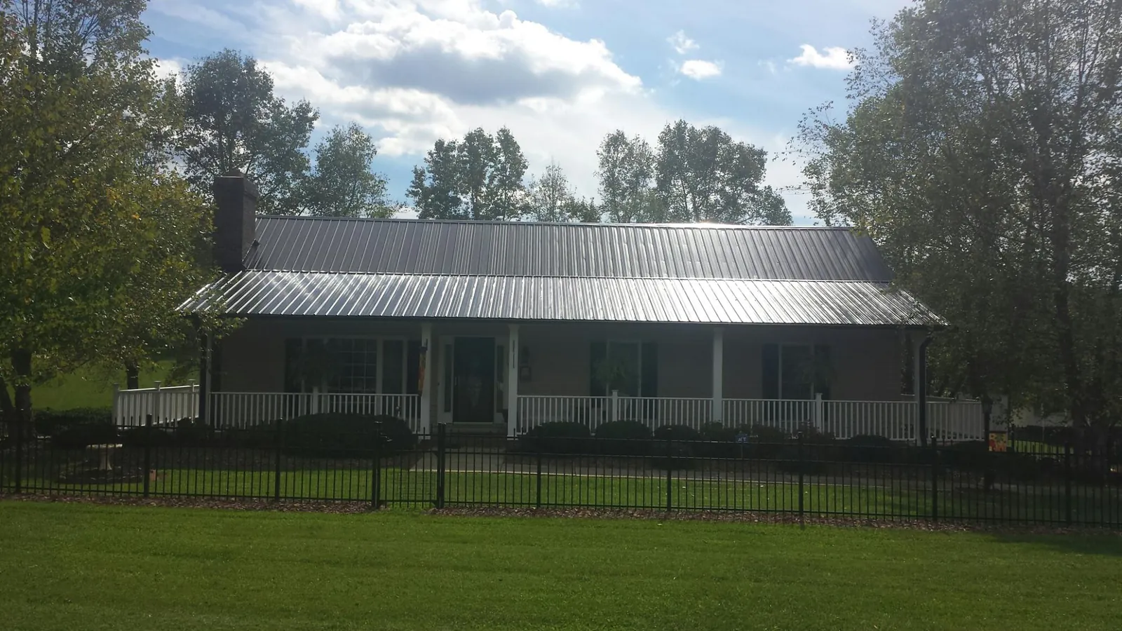 Gray metal roof on a brick ranch with a full width front porch — Gutter Guard Installation work by our crew in Waveland