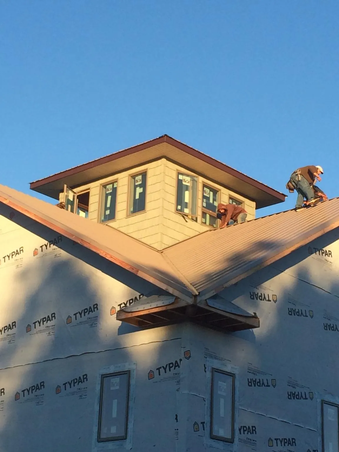 Roofers working around a rooftop cupola on a new metal roof at sunset — Roof Waterproofing in Waveland by Roofing Brothers